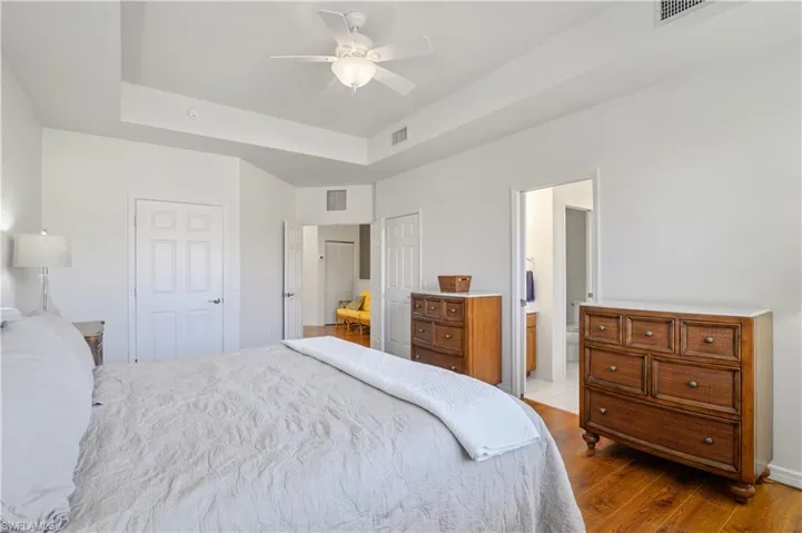 Bedroom featuring dark wood-style flooring, a tray ceiling, and visible vents