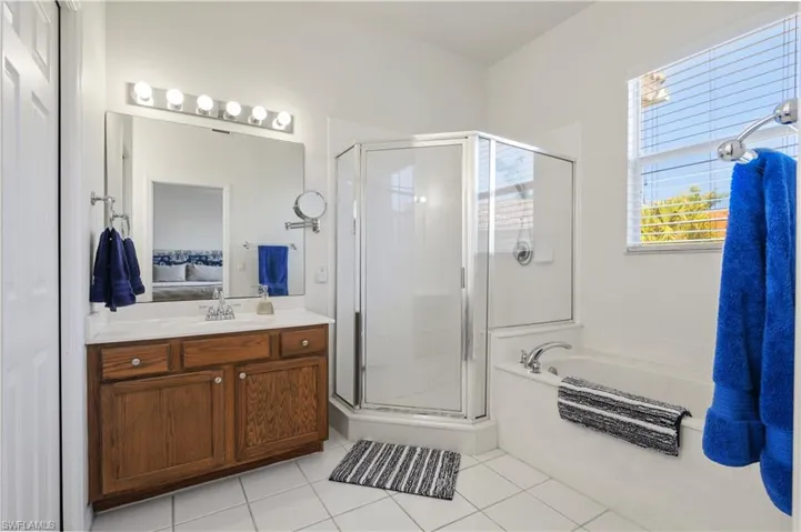Bathroom featuring a stall shower, a bath, tile patterned flooring, connected bathroom, and vanity