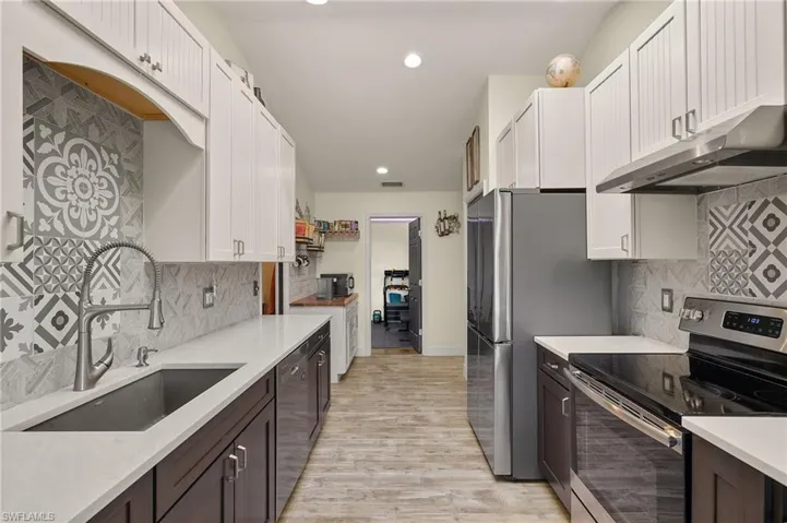 Kitchen with white cabinetry, stainless steel appliances, sink, and dark brown cabinets