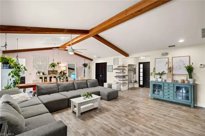 Living room featuring ceiling fan, light hardwood / wood-style floors, and vaulted ceiling with beams