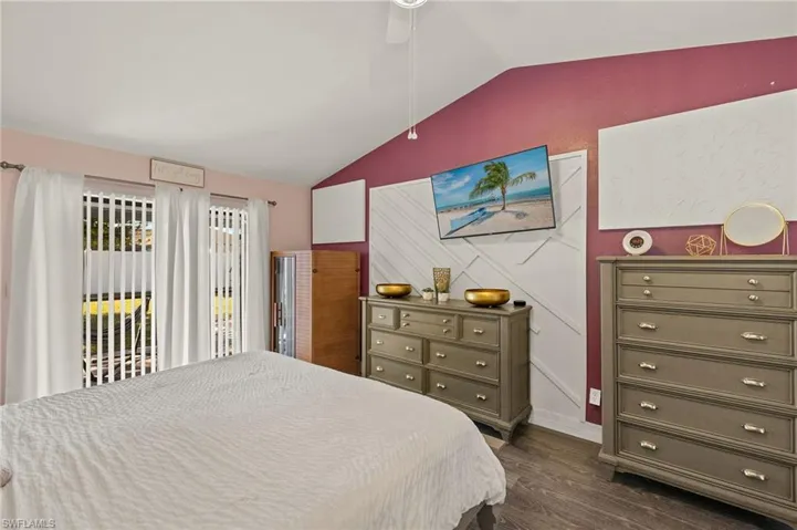 Bedroom with ceiling fan, dark hardwood / wood-style floors, vaulted ceiling, and access to outside