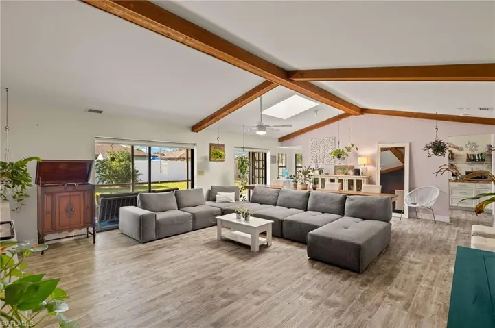 Living room with hardwood / wood-style flooring, lofted ceiling with skylight, and ceiling fan