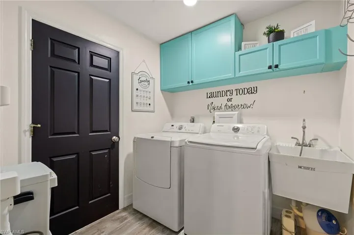 Laundry area featuring cabinets, separate washer and dryer, sink, and light hardwood / wood-style floors