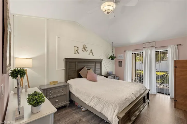 Bedroom with access to exterior, dark wood-type flooring, vaulted ceiling, and ceiling fan
