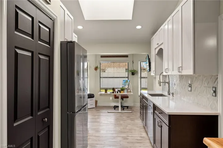 Kitchen featuring appliances with stainless steel finishes, tasteful backsplash, sink, white cabinets, and dark brown cabinets
