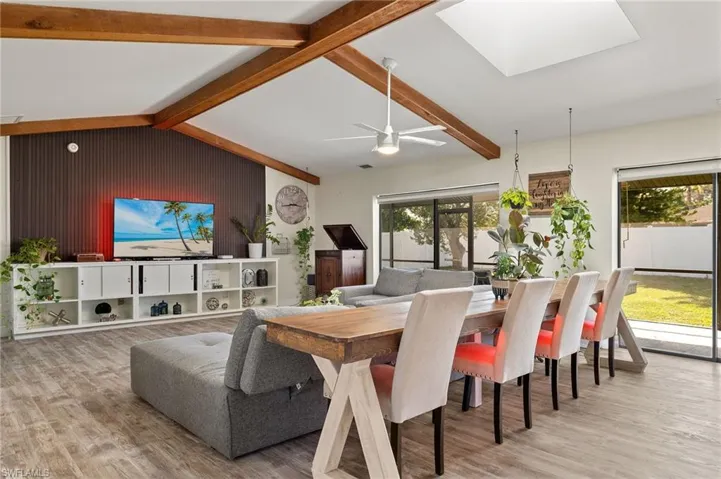 Dining space with lofted ceiling with skylight and light wood-type flooring