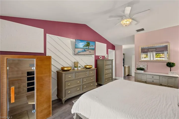 Bedroom with lofted ceiling, ensuite bath, dark hardwood / wood-style flooring, and ceiling fan
