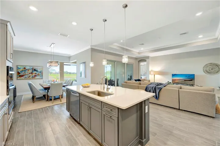 Kitchen with appliances with stainless steel finishes, decorative light fixtures, sink, and a center island with sink