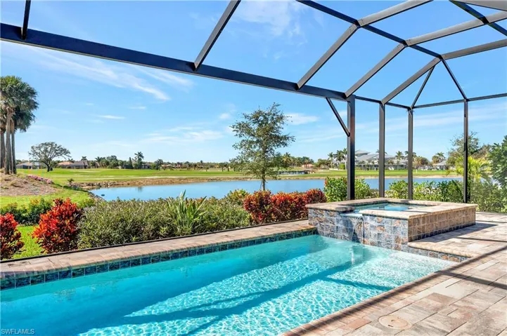 View of pool featuring a water view, an in ground hot tub, a lanai, and pool water feature