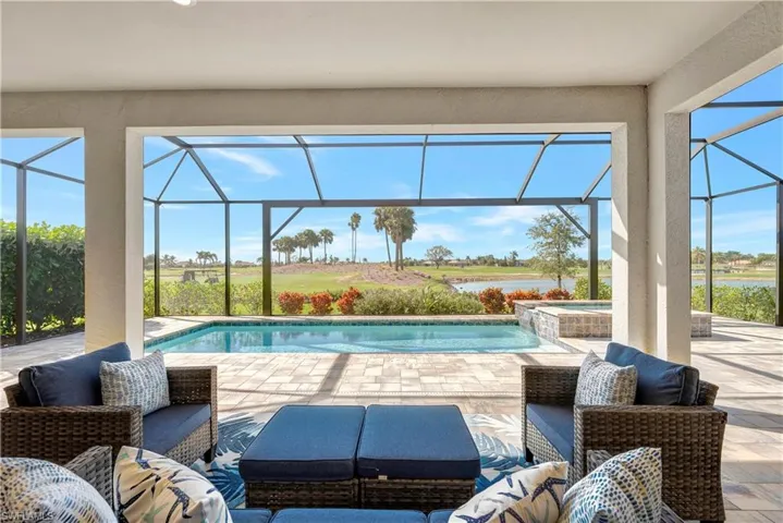 View of pool with a lanai, a patio area, a water view, and an in ground hot tub