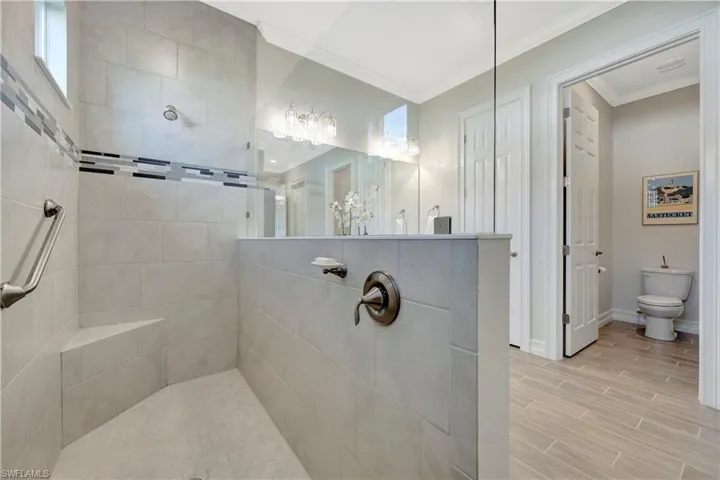 Bathroom with ornamental molding, tiled shower, and toilet