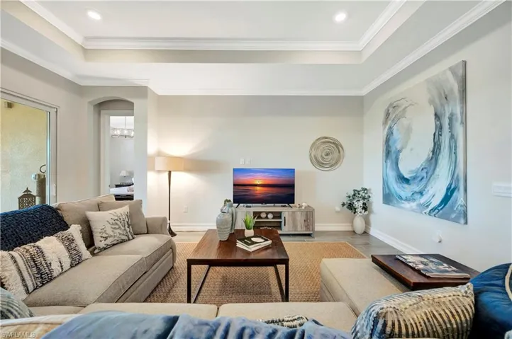Living room featuring crown molding, light hardwood / wood-style floors, and a tray ceiling