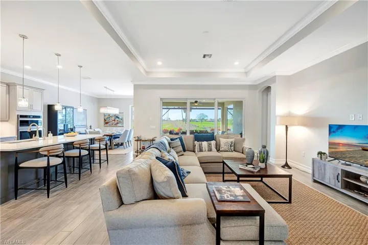 Living room featuring crown molding, a tray ceiling, and light wood-type flooring