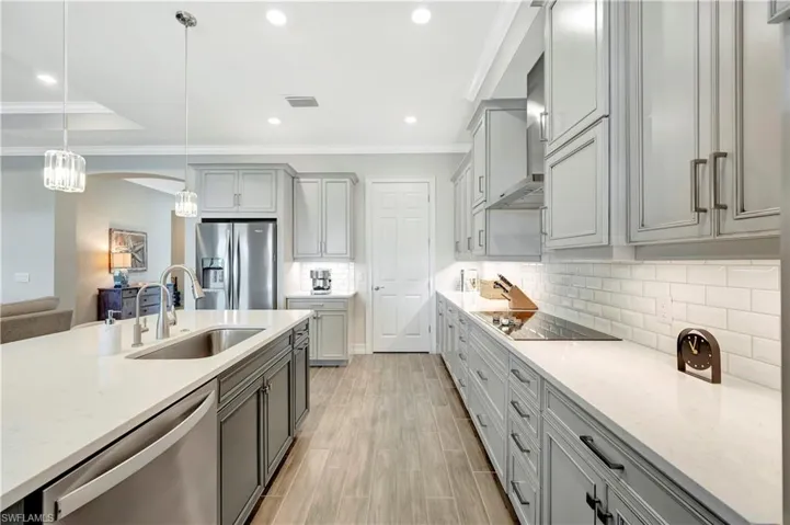Kitchen featuring gray cabinets, pendant lighting, sink, stainless steel appliances, and light stone countertops