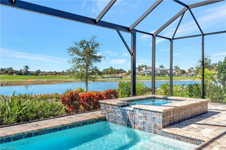 View of pool with a lanai, a patio, a water view, pool water feature, and an in ground hot tub