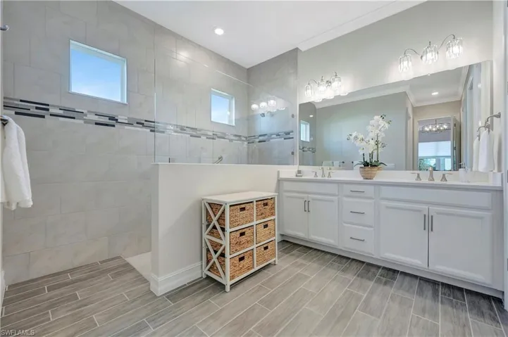 Bathroom with vanity, crown molding, and a tile shower