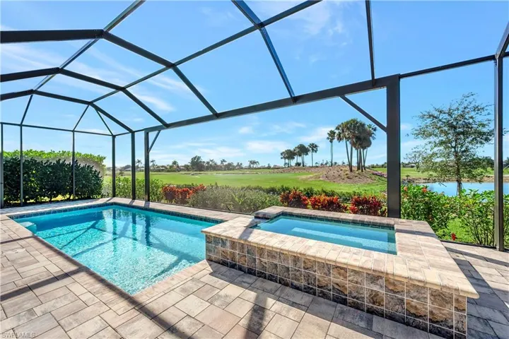 View of pool with an in ground hot tub, glass enclosure, and a patio area