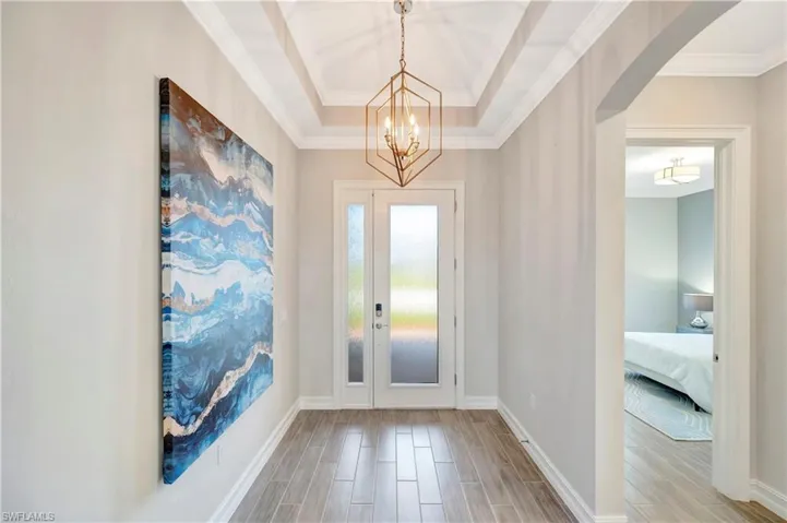 Foyer with a notable chandelier, ornamental molding, and a raised ceiling