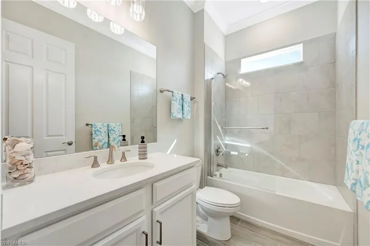 Full bathroom featuring hardwood / wood-style floors, tiled shower / bath combo, vanity, toilet, and crown molding