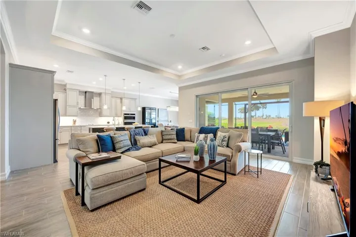 Living room featuring a tray ceiling, crown molding, and light wood-type flooring