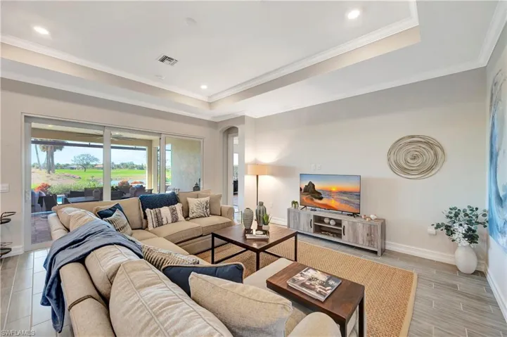 Living room with crown molding, tray ceiling, and light tile floors