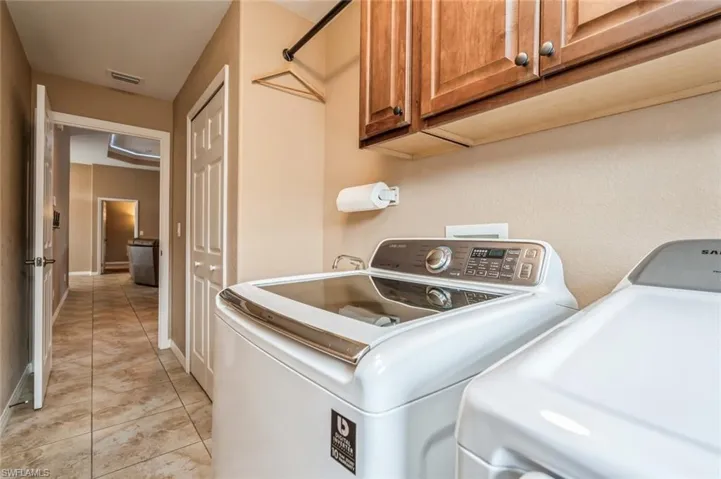 Laundry room with washer and dryer, cabinets, and light tile flooring