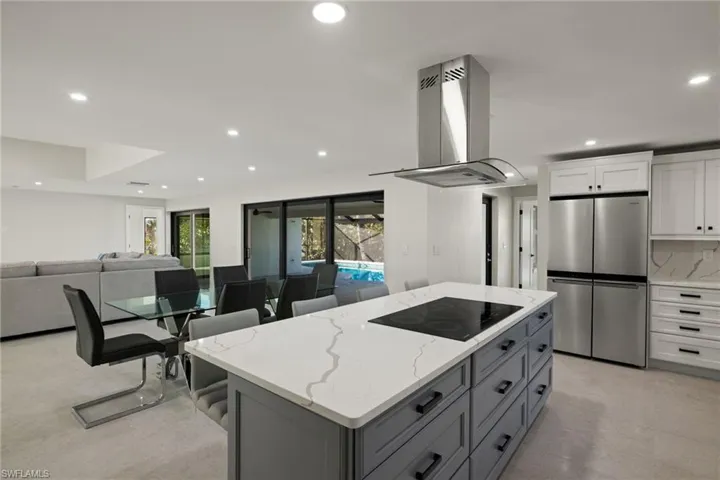 Kitchen with stainless steel fridge, black electric cooktop, island range hood