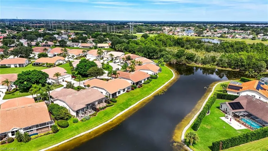 Aerial view of residential area featuring a nearby body of water and a tree filled landscape
