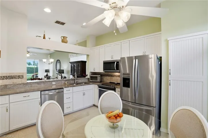 Kitchen featuring a ceiling fan, appliances with stainless steel finishes, white cabinetry, tasteful backsplash, and dark stone countertops
