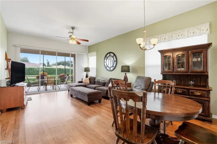 Dining area with light wood-style flooring, ceiling fan, and a chandelier