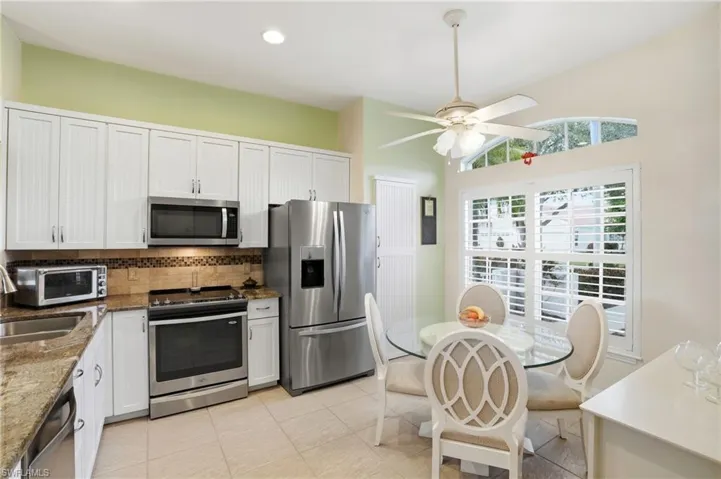 Kitchen featuring dark stone counters, appliances with stainless steel finishes, decorative backsplash, white cabinetry, and recessed lighting