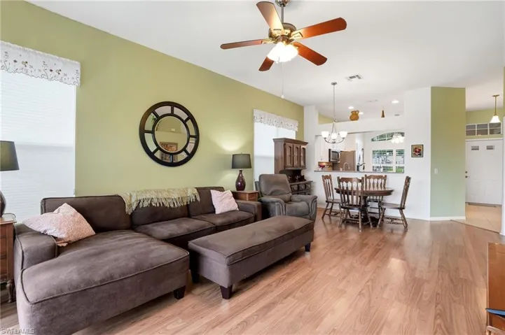 Living room featuring light wood finished floors, ceiling fan, and a chandelier