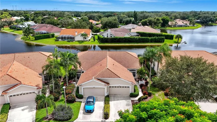 Aerial view of residential area with a large body of water and a tree filled landscape