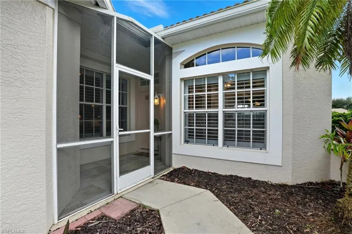 Property entrance with stucco siding and a sunroom