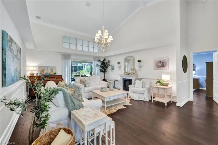 Living room featuring high vaulted ceiling, dark hardwood / wood-style floors, a chandelier, and ornamental molding