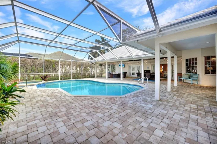 View of swimming pool with ceiling fan, glass enclosure, a patio area, and an in ground hot tub