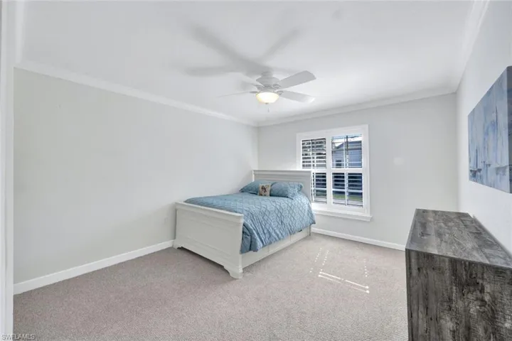 Bedroom with ceiling fan, crown molding, and carpet floors