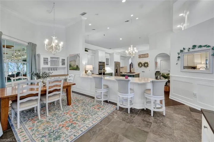 Dining space featuring a towering ceiling, sink, an inviting chandelier, and ornamental molding