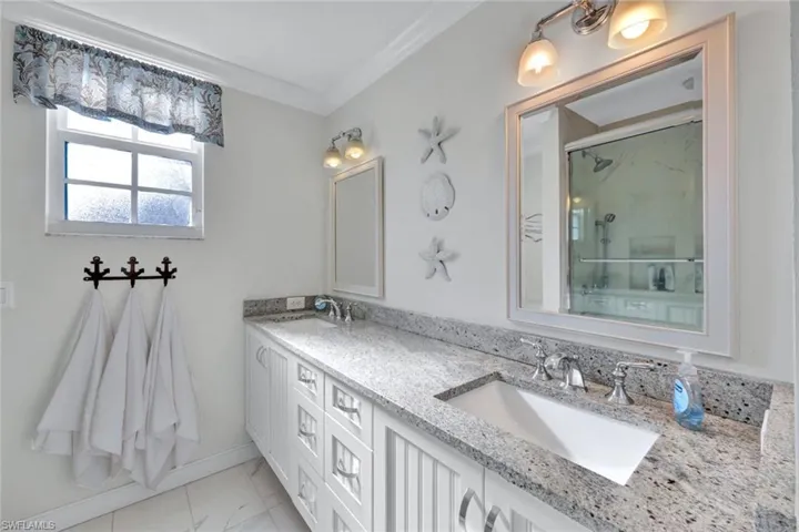 Bathroom featuring an enclosed shower, vanity, and ornamental molding