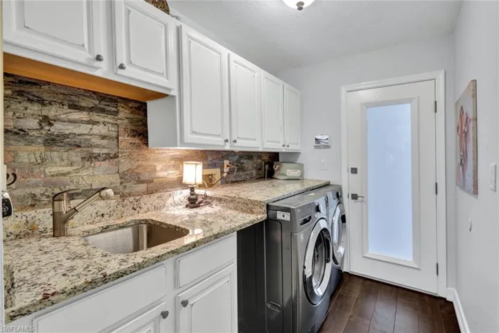 Laundry room featuring washing machine and dryer, cabinets, dark hardwood / wood-style floors, and sink