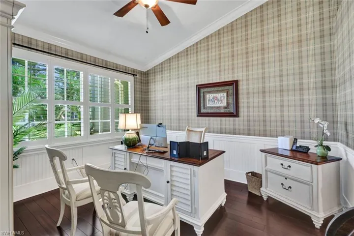 Office area with vaulted ceiling, crown molding, a healthy amount of sunlight, and dark hardwood / wood-style floors