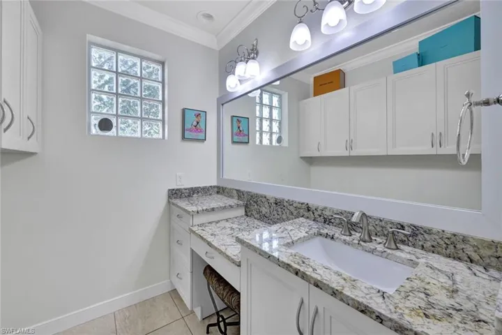 Bathroom with vanity, crown molding, and tile patterned flooring