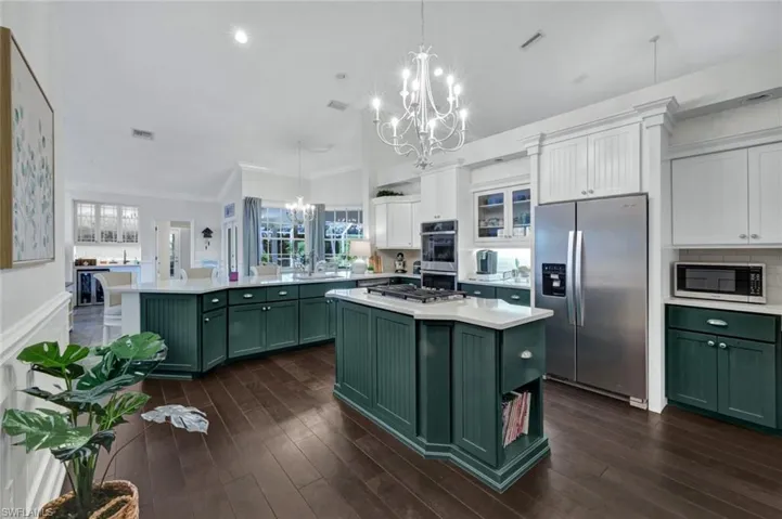 Kitchen featuring a chandelier, stainless steel appliances, light countertops, a center island, and green cabinetry