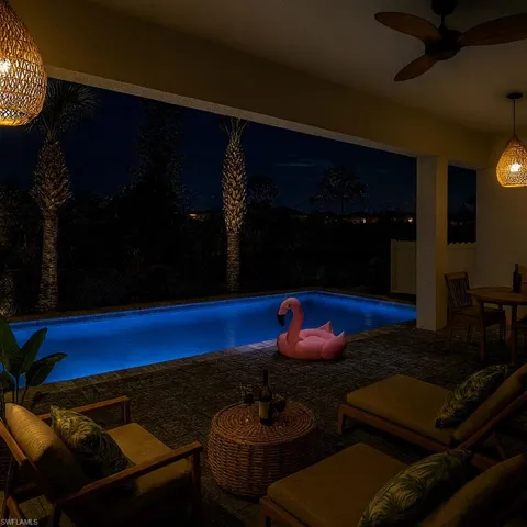 Pool at night with a fenced backyard, an outdoor pool, a patio, a ceiling fan, and an outdoor hangout area
