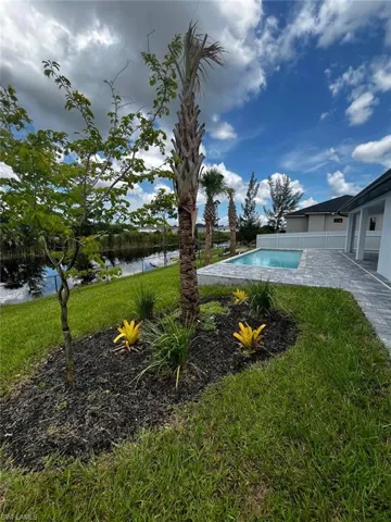 View of swimming pool with a patio area, a water view, and a yard