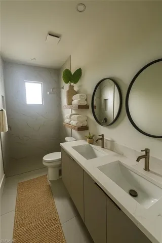 Full bathroom featuring double vanity and a marble finish shower