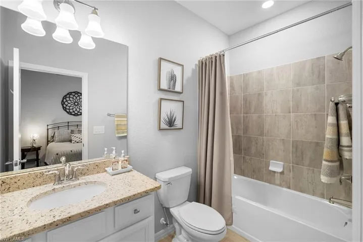 Ensuite bathroom with shower / tub combo with curtain, vanity, and a chandelier