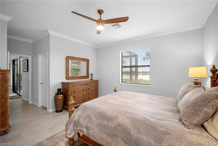 Bedroom featuring ornamental molding, multiple windows, light wood finished floors, and a ceiling fan