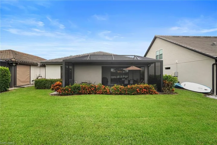 Back of property with a lanai, a lawn, stucco siding, and a sunroom