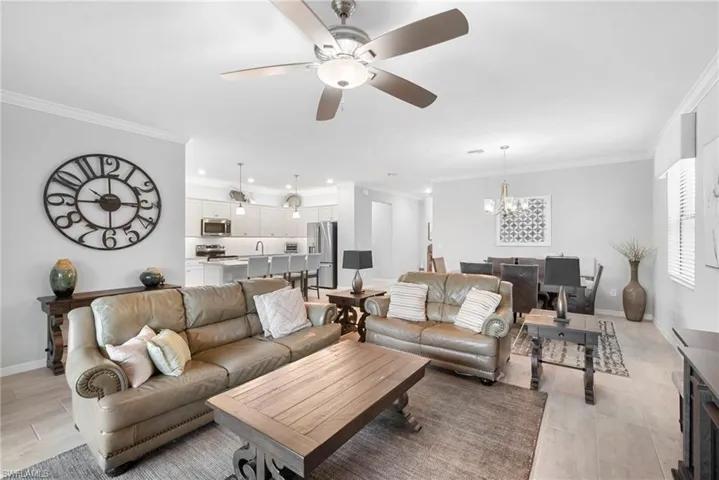 Living room with ornamental molding, ceiling fan, and a chandelier